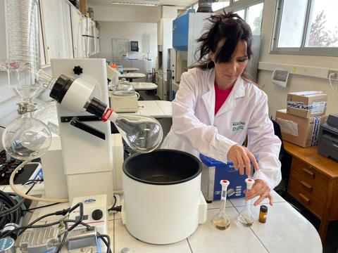 Una mujer en un laboratorio químico realizando un experimento con tubos de ensayo.