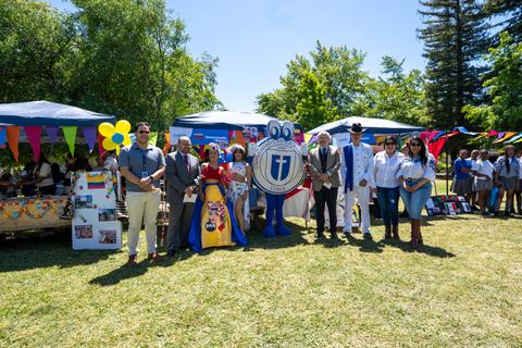 Un grupo de personas sonrientes celebrando en un evento al aire libre con decoraciones coloridas.