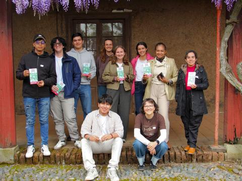 Grupo de estudiantes posando en una casa de campo con folletos en la mano.