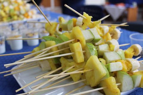 Variadas brochetas de frutas frescas sobre una bandeja.
