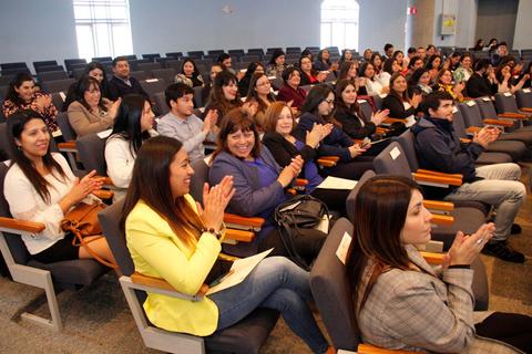 Una multitud de personas aplaudiendo en un evento en un auditorio.