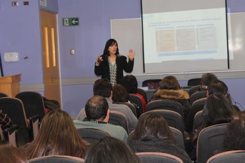 Una presentación en un aula con una mujer de pie explicando frente a un grupo de personas sentadas.