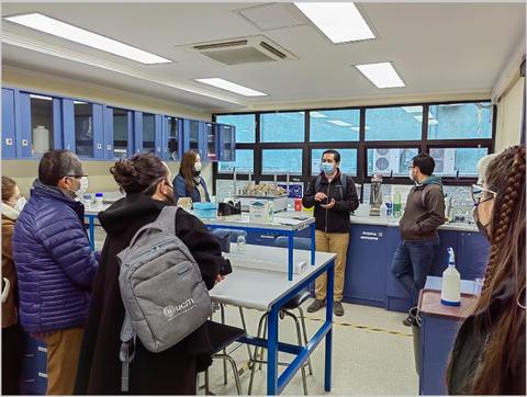 Un grupo de personas escucha a un hombre que está dando una charla en un laboratorio.