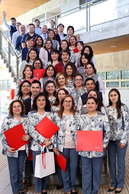 Un grupo numeroso de personas sonrientes posando en una escalera en un ambiente profesional.