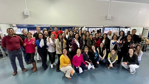 Un grupo grande de personas sonrientes posando juntas en un ambiente cerrado.