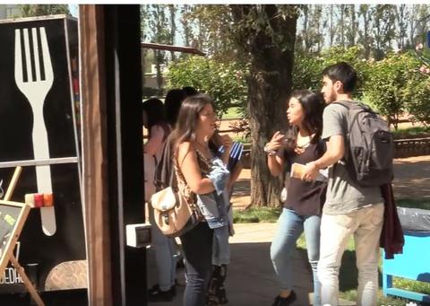 Un grupo de jóvenes conversa animadamente en un ambiente al aire libre cerca de un camión de comida.