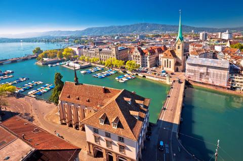 Vista panorámica de la ciudad de Zúrich con el río y barcos en el agua.