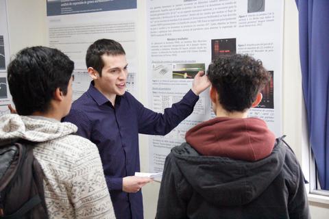 Un joven presenta un proyecto a dos personas en un ambiente académico.