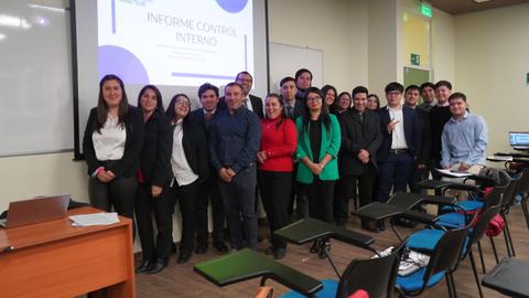 Grupo de personas posando en un aula con un proyecto titulado 'Informe Control Interno' en la presentación.