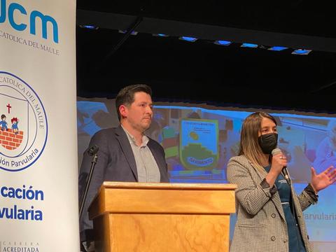 Una presentación en un evento educativo con dos personas en un escenario, una de las cuales está hablando con un micrófono.