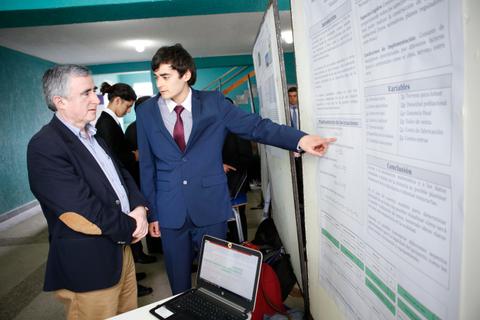 Un joven presenta su investigación a un adulto en un evento académico.