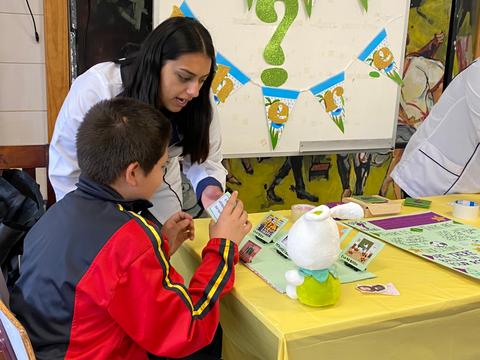 Una mujer interactúa con un niño mientras muestran materiales educativos en una mesa.