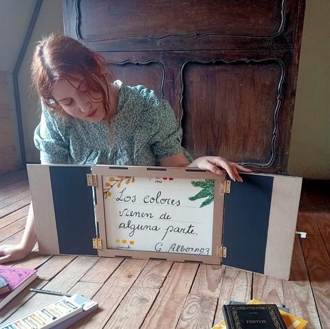 Una joven se encuentra sentada en el suelo, mirando un cuadro con un mensaje sobre los colores.