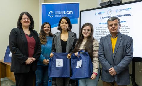 Un grupo de personas posando frente a un banner relacionado con un concurso de microcuentos.