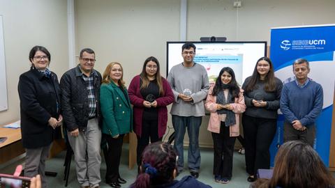 Un grupo de personas posa frente a una pantalla en un evento académico.