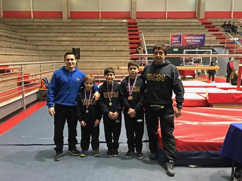 Un grupo de cuatro niños y dos adultos celebran un logro deportivo en un gimnasio.