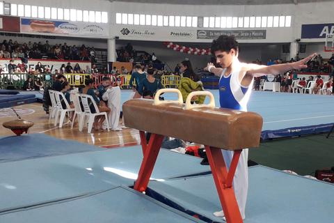 Un gimnasta se prepara para ejecutar un ejercicio en las anillas en un evento deportivo.