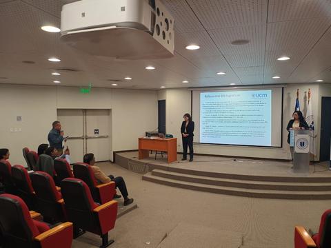 Una presentación en un aula con un ponente frente a una audiencia sentada.