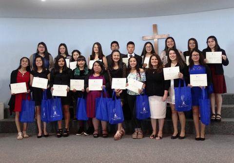 Grupo de estudiantes sosteniendo certificados de graduación en un evento celebratorio.