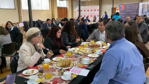 Una reunión social donde varias personas comparten una comida en una mesa.