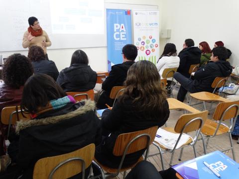 Un grupo de personas asiste a una presentación en un aula con un cartel de PACE en el fondo.