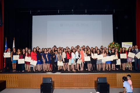Un grupo de graduados posa en un escenario durante una ceremonia de entrega de diplomas.