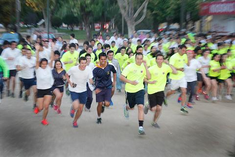 Un grupo de corredores enérgicos participa en una carrera, luciendo camisetas de colores brillantes.
