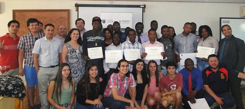 Un grupo de personas sonrientes sostiene certificados en un ambiente de celebración.