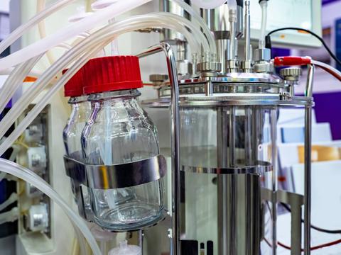 La imagen muestra un equipo de laboratorio con frascos y tubos conectados en un entorno industrial.