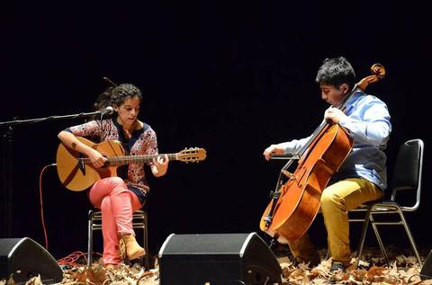 Dos músicos se presentan en un escenario interpretando una pieza musical con guitarra y violonchelo.