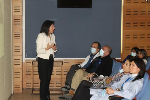 Una presentadora expone ante una audiencia en un salón de conferencias.