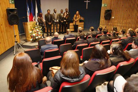 Un grupo de personas está de pie en un escenario mientras un auditorio observa atentamente.