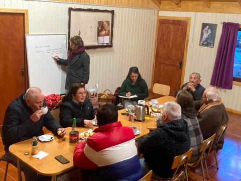 Un grupo de personas compartiendo y conversando en una reunión en un lugar acogedor.