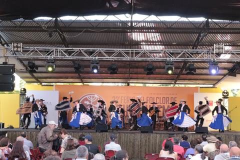 Un grupo de bailarines en trajes tradicionales se presenta sobre un escenario en un festival folclórico.