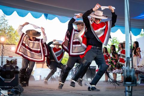 Un grupo de hombres bailando en un escenario, vestidos con trajes tradicionales chilenos.