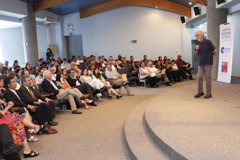 Un orador está hablando frente a un público en un auditorio.