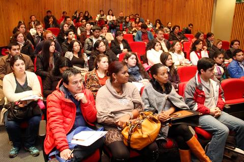 Una multitud de personas atentas en una sala de conferencias.