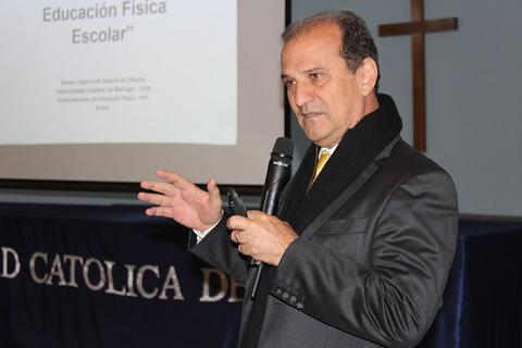 Un hombre vestido de traje habla en una conferencia sobre educación física escolar.