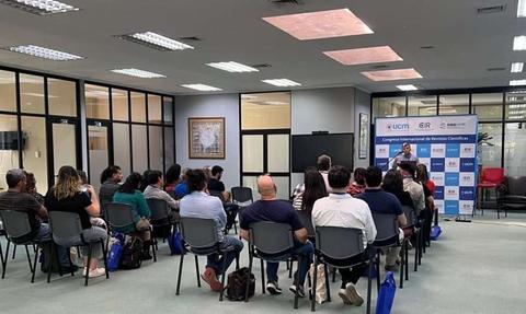 Una reunión de un congreso académico con varios asistentes prestando atención al expositor.