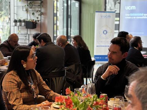 Un par de personas conversando en un ambiente de reunión empresarial.