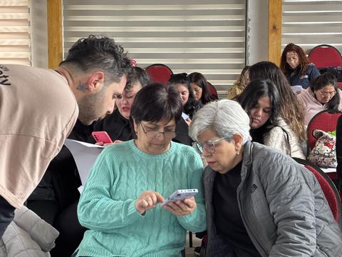 Un grupo de personas se reúne para aprender a usar sus teléfonos en un ambiente colaborativo.