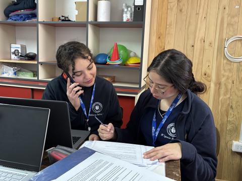 Dos jóvenes conversando y trabajando en un proyecto en una oficina.