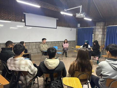 Un grupo de jóvenes participa en una conversación en círculo en un aula.