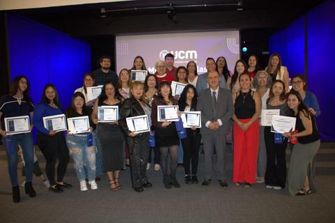 Una ceremonia de entrega de certificados con un grupo de personas sonrientes en un escenario.