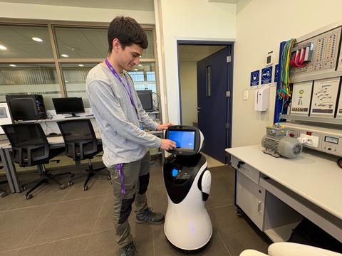 Un cabro está interactuando con un robot en un laboratorio.