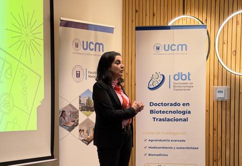 Una mujer está presentando un tema en una conferencia de biotecnología en un ambiente profesional.