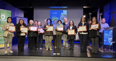 Un grupo de personas sonrientes sosteniendo certificados en un evento de entrega de reconocimientos.