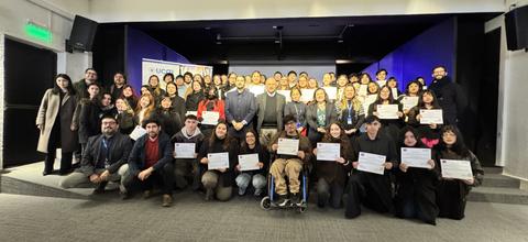 Un grupo numeroso de personas posando con certificados en un evento en Chile.