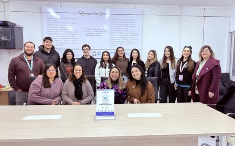 Un grupo de personas sonrientes en una reunión formal en una oficina.