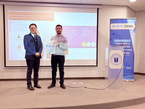 Un par de hombres en un evento de presentación, uno de ellos sosteniendo un documento.